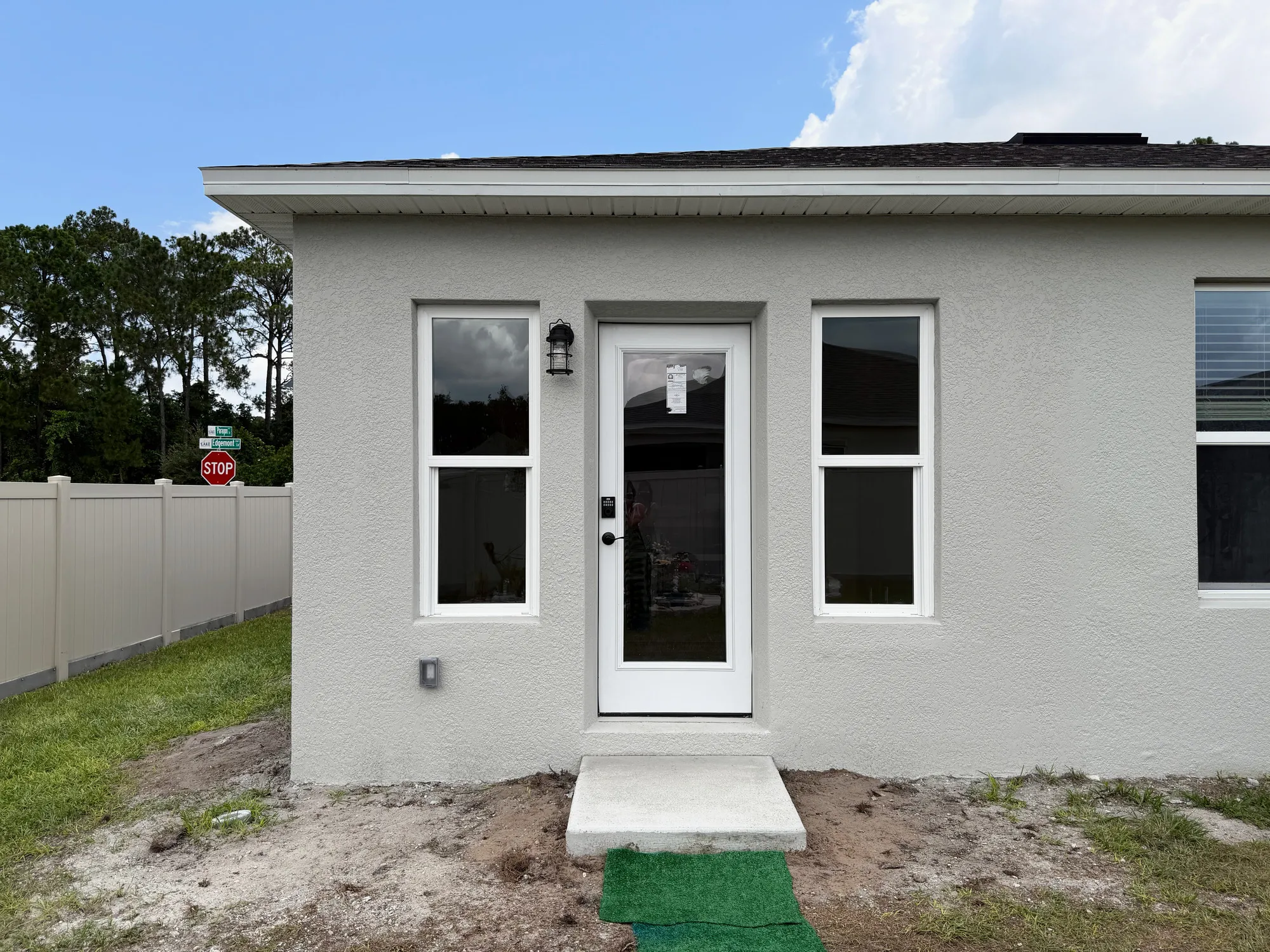 Finished stucco patio enclosure with a glass door, two windows, and a concrete entry step.